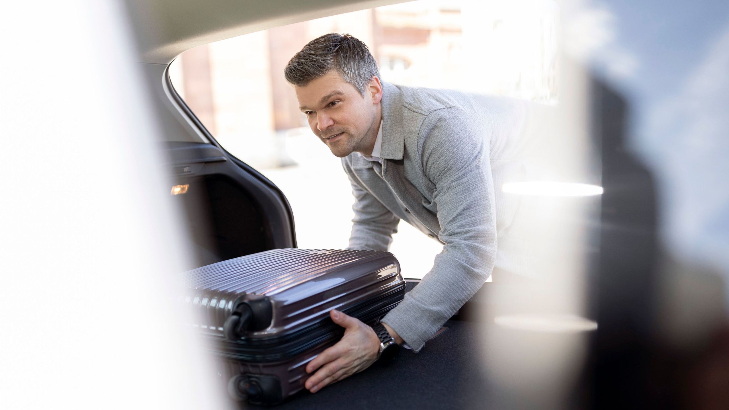Mann verstaut einen Koffer im Kofferraum