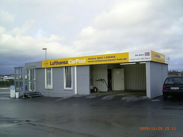Building with a 'Lufthansa CarPool' sign and DB logo.
